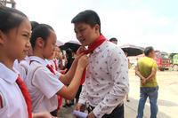 古定中心小学学生为每一位到场宾客系上红领巾